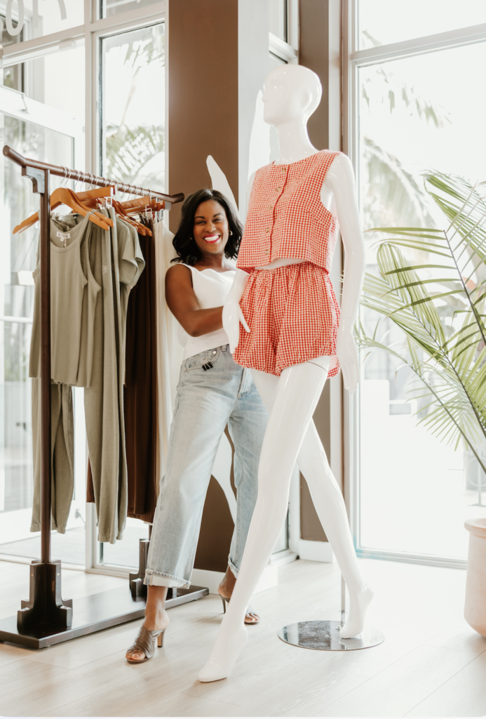Nasheema, co-owner of ZOË Palm Beach Gardens, posing beside a mannequin inside the boutique.